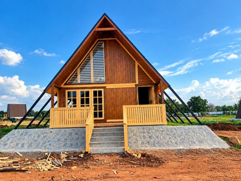Modern wooden A-frame cottage with elevated porch and contemporary exterior design.