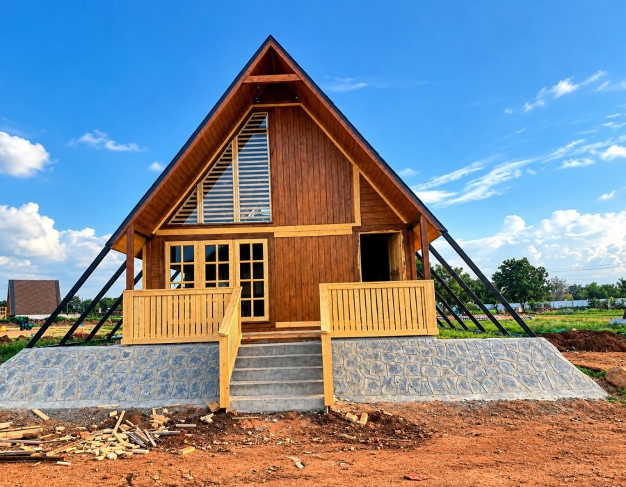 Modern wooden A-frame cottage with elevated porch and contemporary exterior design.